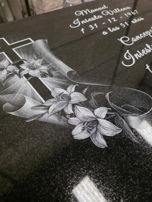 Grabado de lirios y cinta conmemorativa sobre granito negro